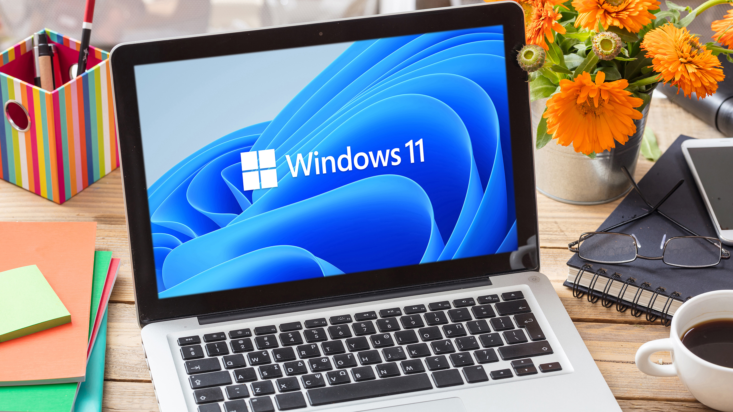 Signo de marca oficial de Windows 11 en la pantalla de la computadora portátil, mesa de oficina comercial