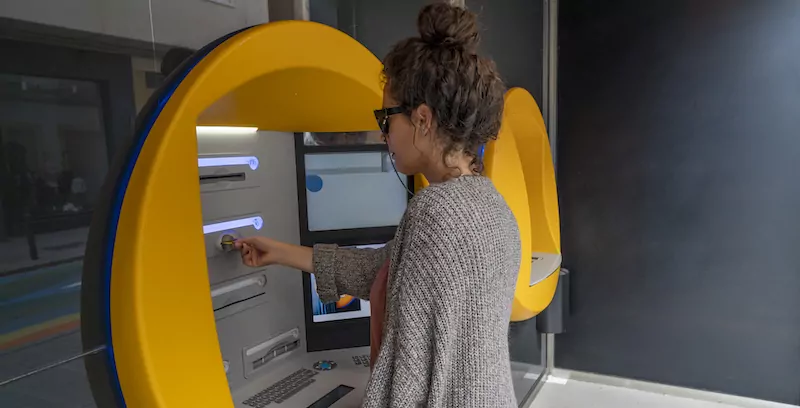 ATM을 사용하는 젊은 여성의 측면. 안달루시아에서 찍은. 스페인 남부.