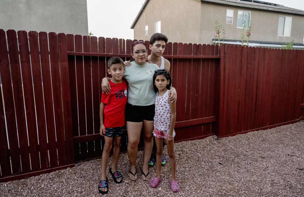 Một người phụ nữ và ba đứa trẻ tạo dáng trước hàng rào sân sau.