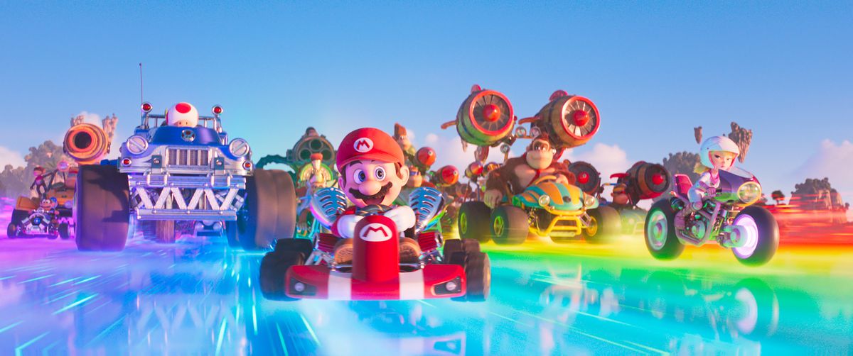 Mario en de cast van de Mario Bros. Movie in hun Mario Kart-voertuigen terwijl ze over Rainbow Road razen.