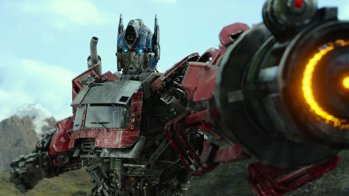 Transformers: Rise of the Beasts에서 Optimus Prime(Peter Cullen)이 팔에 장착된 에너지 캐논을 겨냥하고 있습니다.