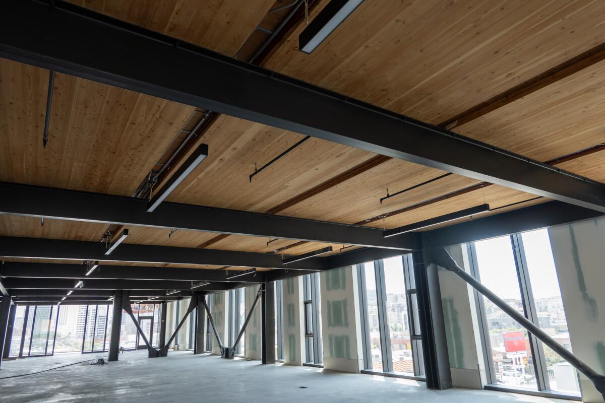 Ein leerer Büroraum im Dachgeschoss ist mit einer Decke aus großen Massivholzbrettern verkleidet
