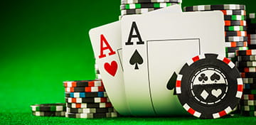 Fichas de póquer apiladas y una mano de póquer de cinco cartas