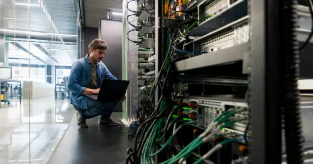 Técnico informático latinoamericano arreglando un servidor de red en la oficina: enfoque en primer plano