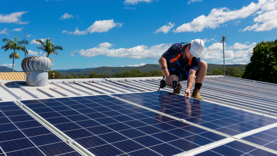 Techniker bohrt Solarpaneele auf dem Dach eines Hauses