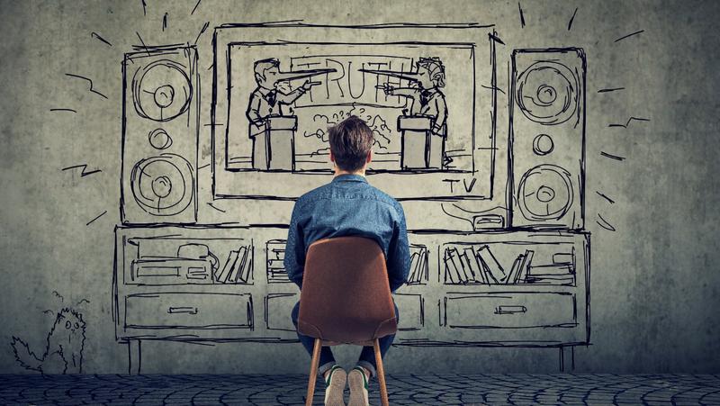 Man seen from behind sitting in a chair and looking at a wall with a line drawing of an entertainment center with a TV showing two people with their noses growing long signifying that they're lying, photo by SIphotography/Getty Images