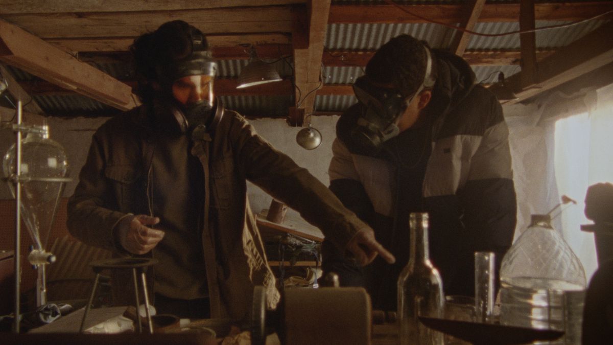 パイプラインを爆破する方法でガスマスクを着用した XNUMX 人の人物が化学薬品を扱っています。