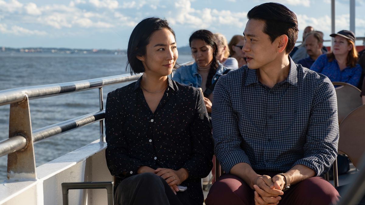 Nora and Hae Sung sit on a ferry, going to the Statue of Liberty.