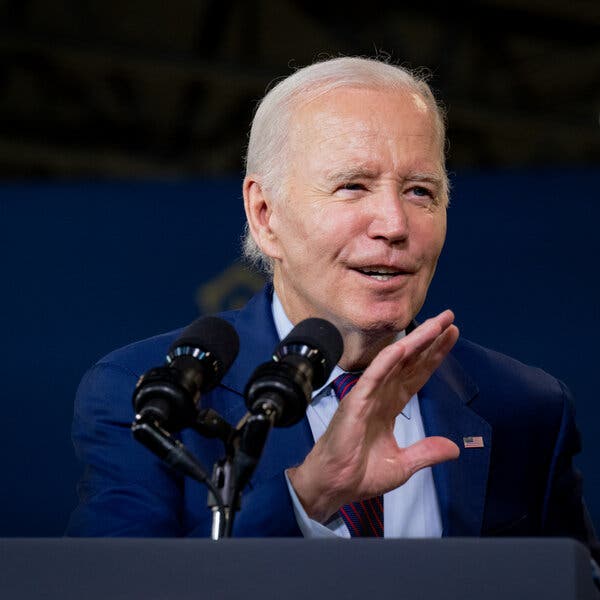 President Biden speaks into a microphone held in his left hand while gesturing with his right hand.