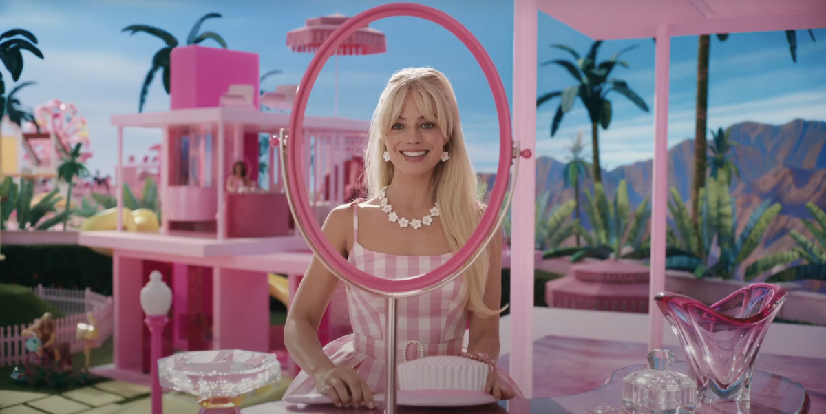 Barbie (Margot Robbie) yuvarlak ayna çerçevesinden bakıp gülümsüyor