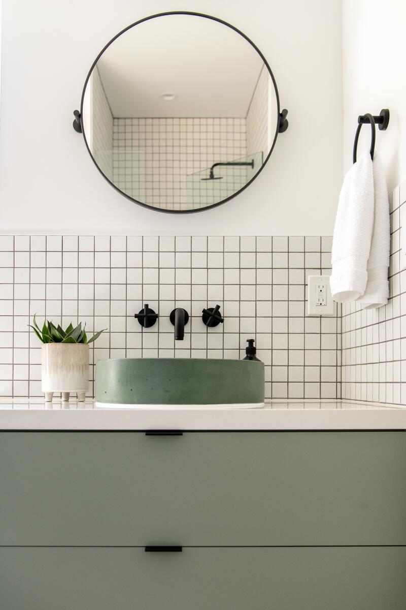 Een badkamer met witte tegels en groene kast