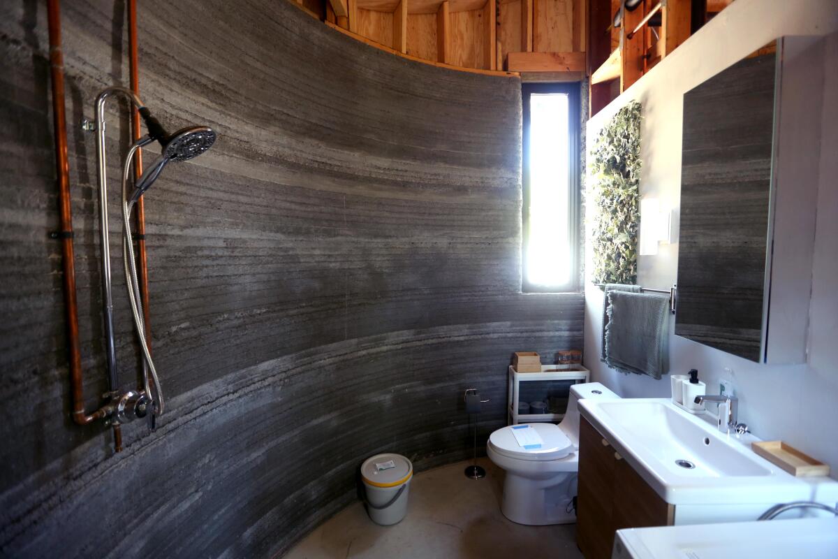 Een zicht op een badkamergedeelte met een zacht gebogen muur gemaakt van slanke horizontale richels van beton