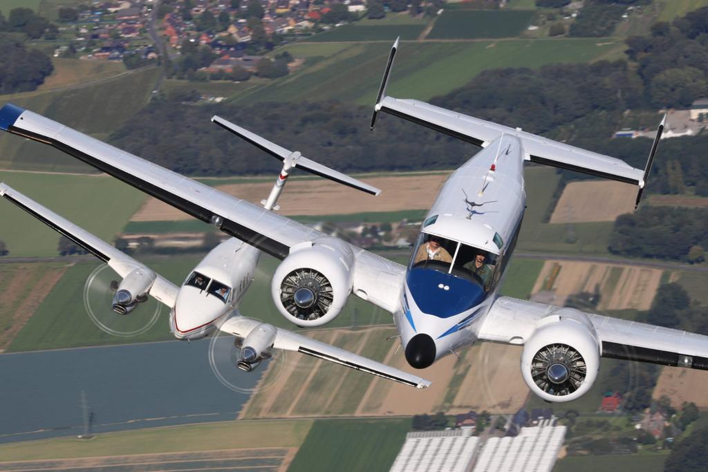 Yan yana süzülen Beechcraft 18 ve onun evrimsel halefi King Air, aşağıdaki Dünya'nın arka planında dinamik bir havacılık mükemmelliği mirasını sergiliyor.
