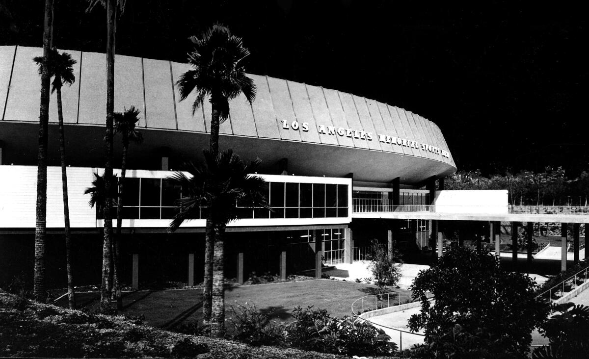 Ein Schwarz-Weiß-Foto eines runden Gebäudes mit Palmen.