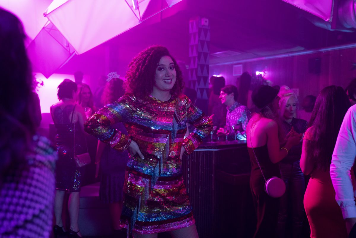 Rose Matafeo, Starstruck'ta elleri kalçalarında ışıltılı bir elbiseyle bir kulüpte duruyor.