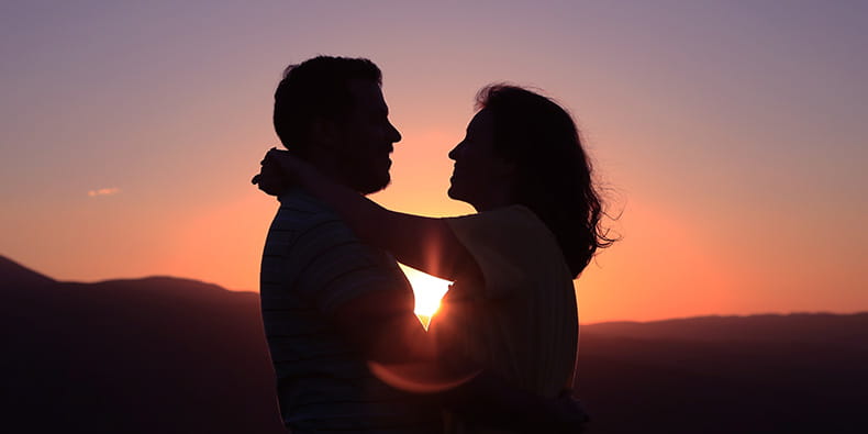 Twee mensen knuffelen in de zonsondergang