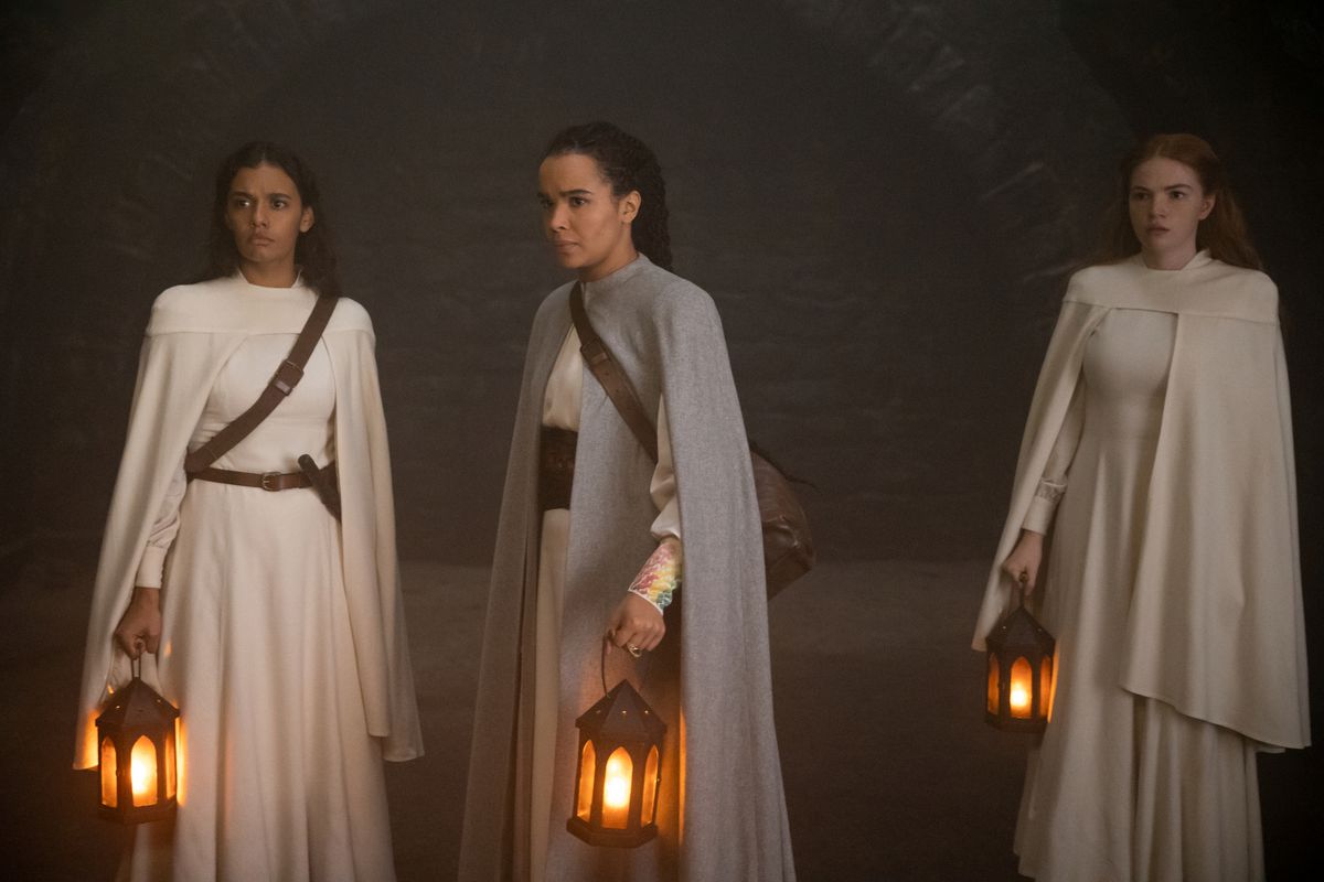 Nynaeve (Zoë Robins), Egwene (Madeleine Madden) y Elayne (Ceara Coveney) están de pie con linternas mirando algo.