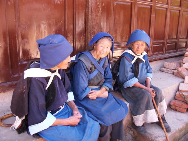 Three elder women sit on a bench