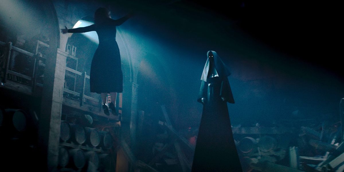En kvinne flyter hjelpeløs foran en høy truende figur med glødende øyne i nonneantrekk i The Nun 2.