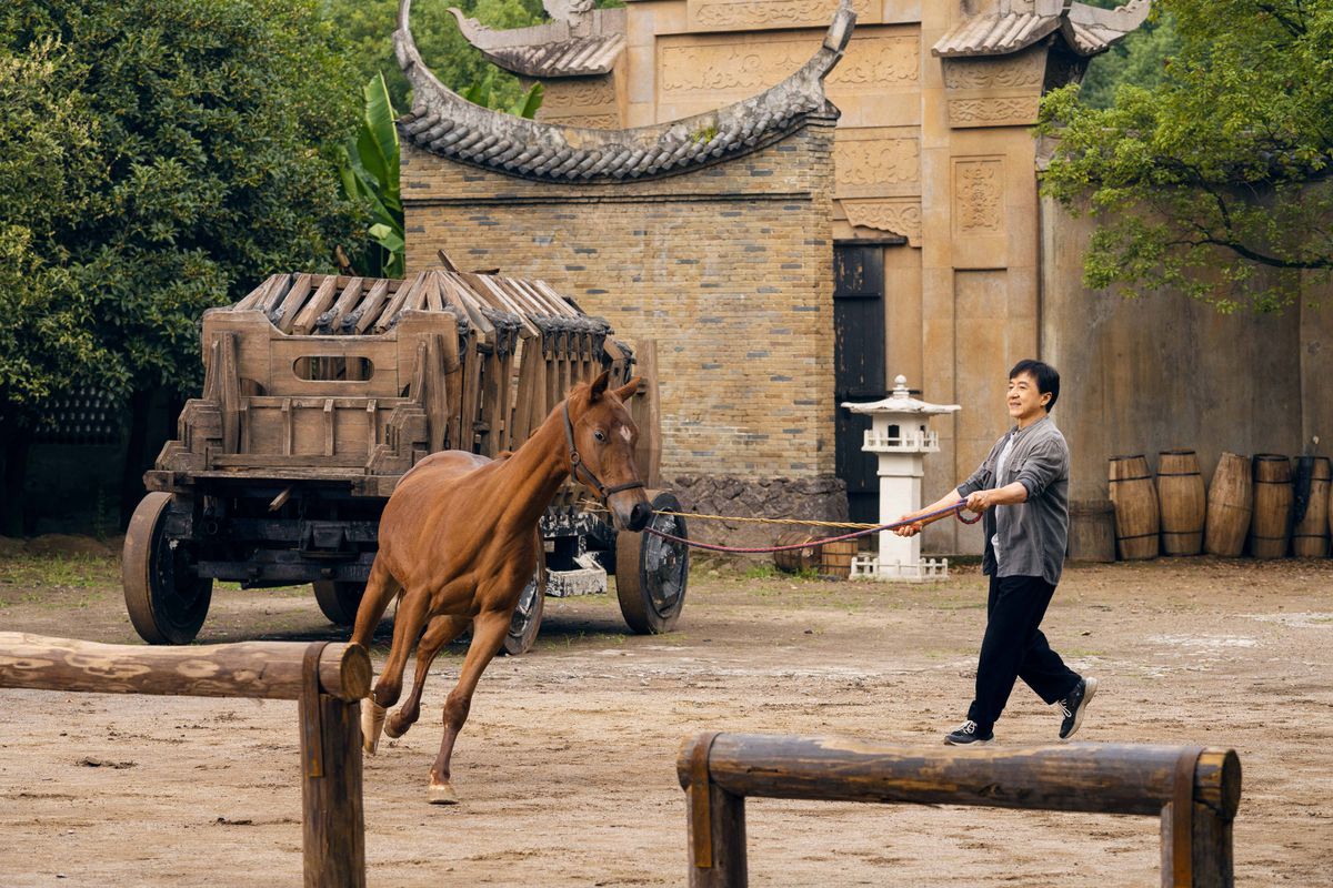 En hest galopperer rundt et åpent område mens Jackie Chan instruerer i Ride On.
