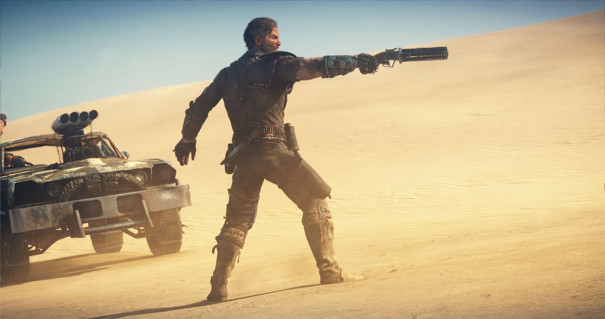 Een man richt een pistool naar rechts in een woestijnlandschap in Mad Max