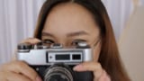 Een vrouwelijke fotograaf met een bril en een camera in de hand