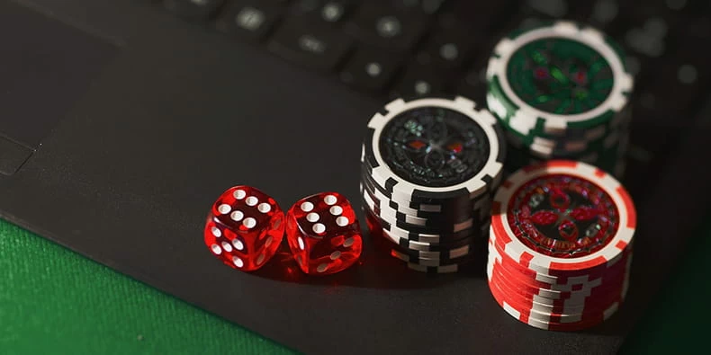 Casinofiches en dobbelstenen geplaatst over een laptop