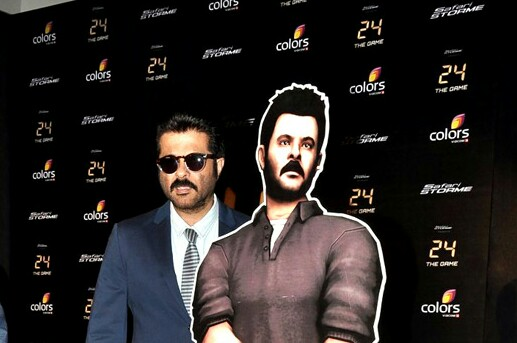 Anil Kapoor in a navy blue suit next to a chardboard cutout of his character in the "24" game. 