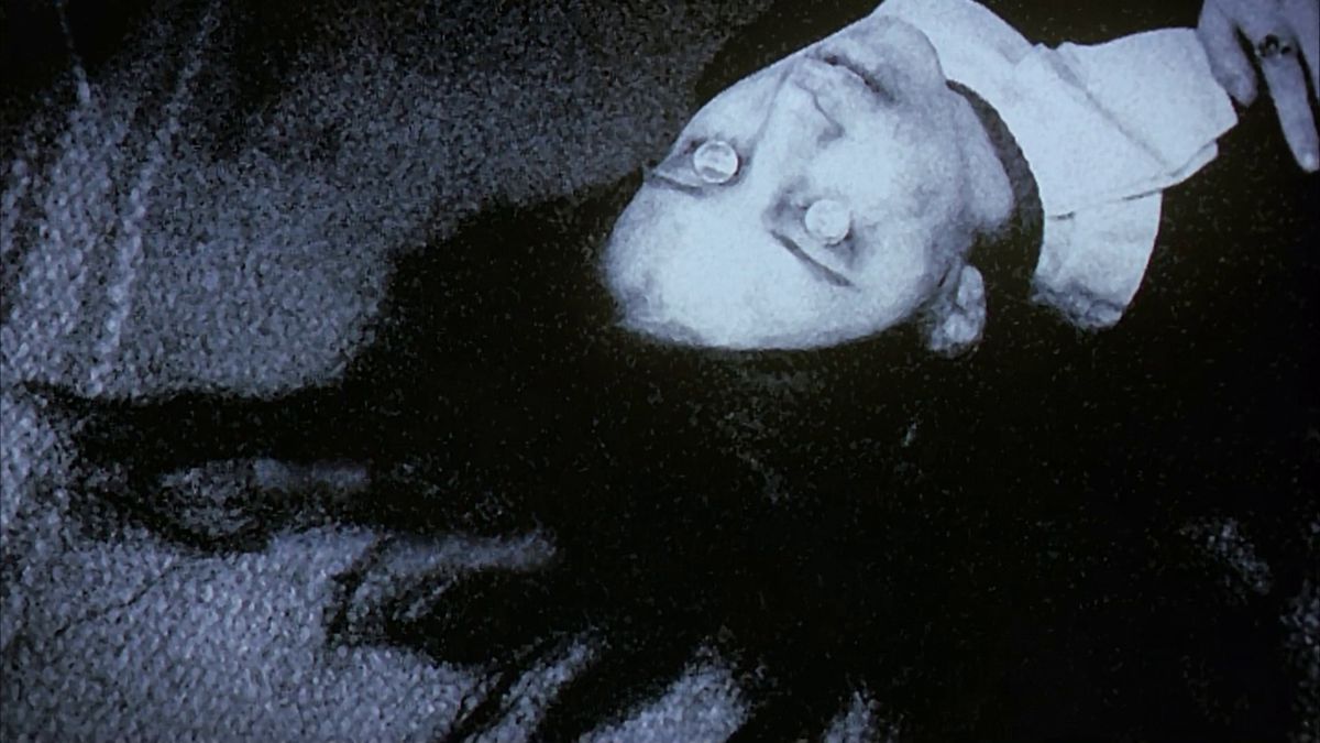 Ginger Snaps'te göz kapaklarının üzerinde bozuk paralar bulunan ölü bir kadının siyah beyaz fotoğrafı.