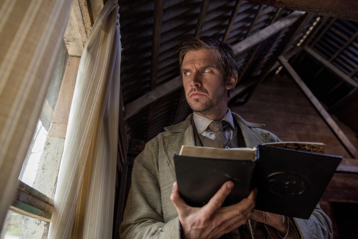 Dan Stevens as Thomas Richardson in Apostle looks out the window suspiciously while reading The Bible