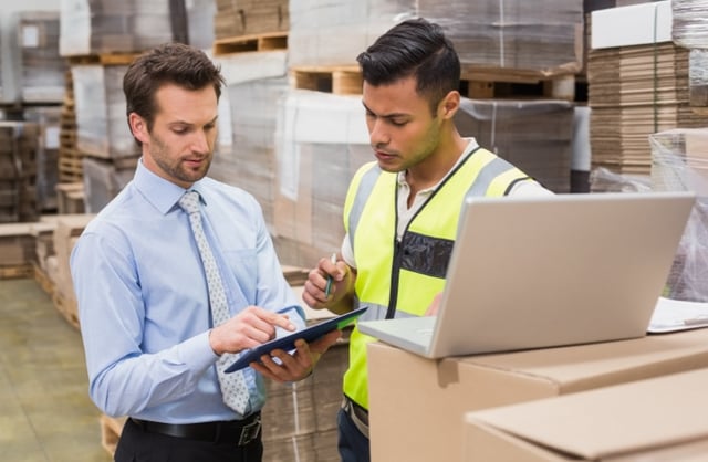Warehouse manager and employee discussing order processing metrics