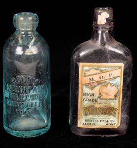 Dos botellas: una de ellas, una botella de refresco de agua para Rocky Mountain Bottling Works (Marysville, Montana); el otro, una botella de media pinta de whisky de alta calidad MOP (Alder, Montana) con etiqueta de papel: alcanzó los 593.75 dólares.