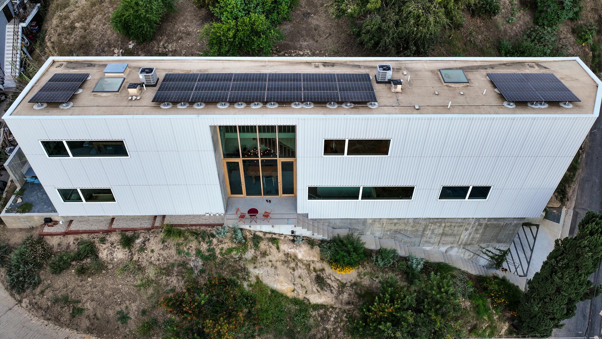From above, you see the tall, skinny and long home with big vertical windows and solar panels on the roof. 