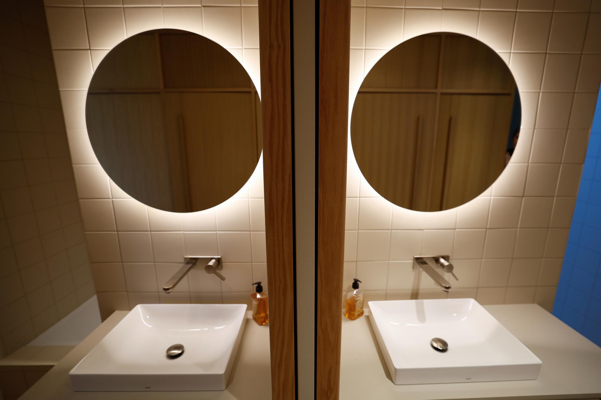La luz brilla detrás de un espejo encima de un lavabo y se refleja en un espejo.