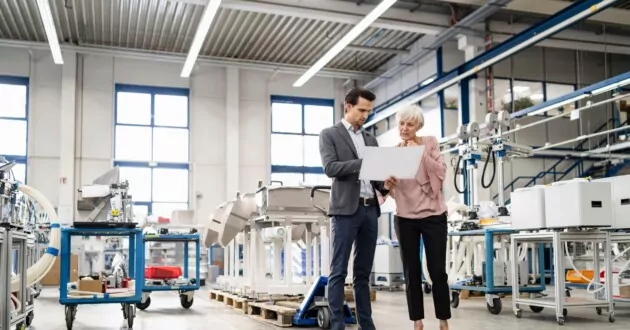 Forretningsmann og seniorkvinne ser på plan i en fabrikk for å implementere ERP-systemer