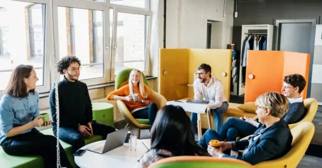 여러 비즈니스 직원이 사무실에서 회의를 하는 동안 함께 앉아서 직원 경험 전략을 브레인스토밍합니다.