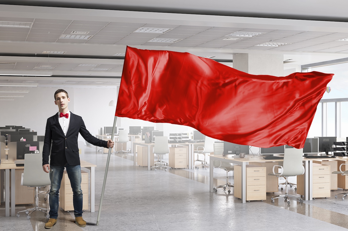 Hombre ondeando bandera roja advirtiendo en empresa de tecnología vacía