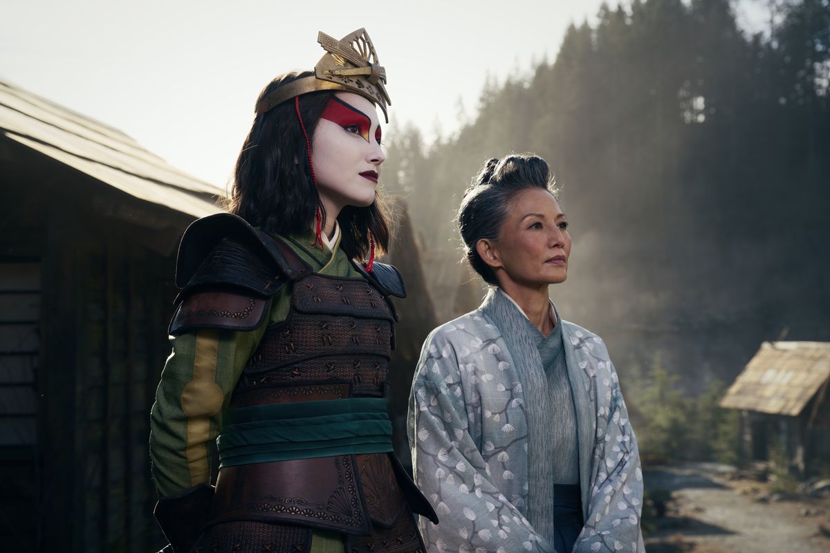 Suki uit de live-actionversie van Avatar: The Last Airbender in volledige Kyoshi Warrior-outfit, naast burgemeester Yukari