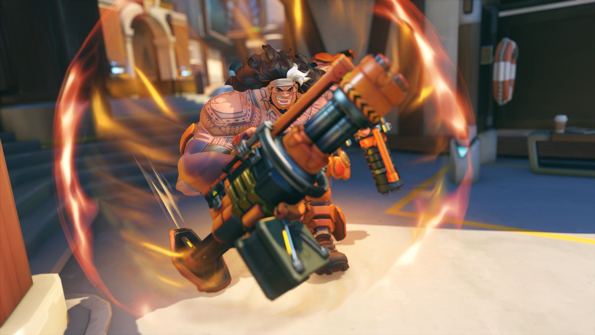A grinning Mauga runs toward the camera using his Overrun ability in a screenshot from Overwatch 2