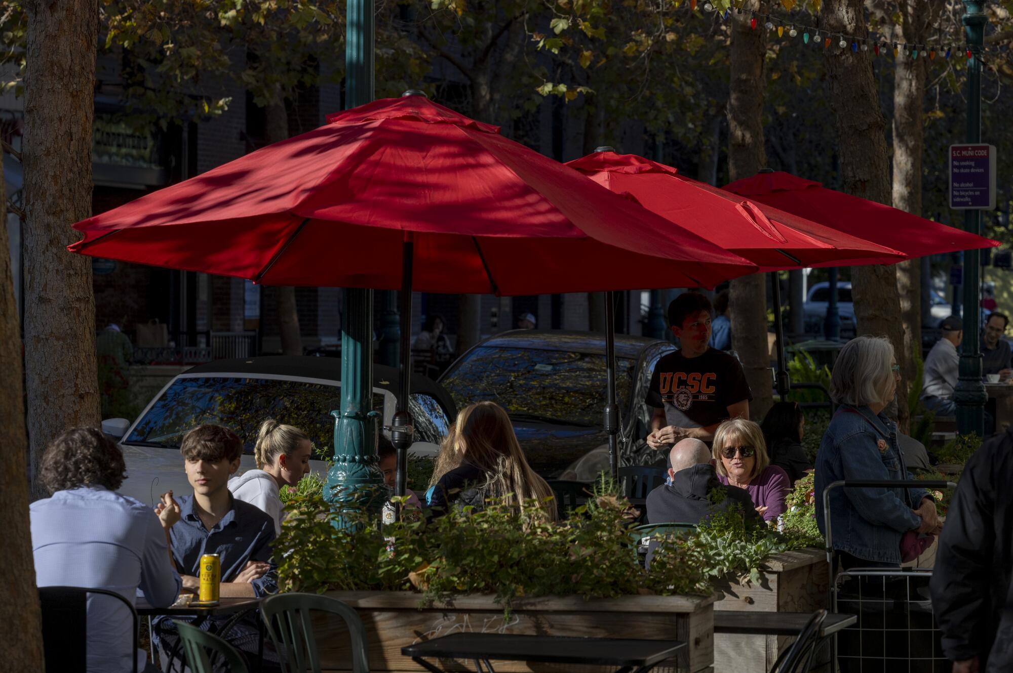 Yemek yiyenler Santa Cruz şehir merkezinde açık havada oturuyorlar.