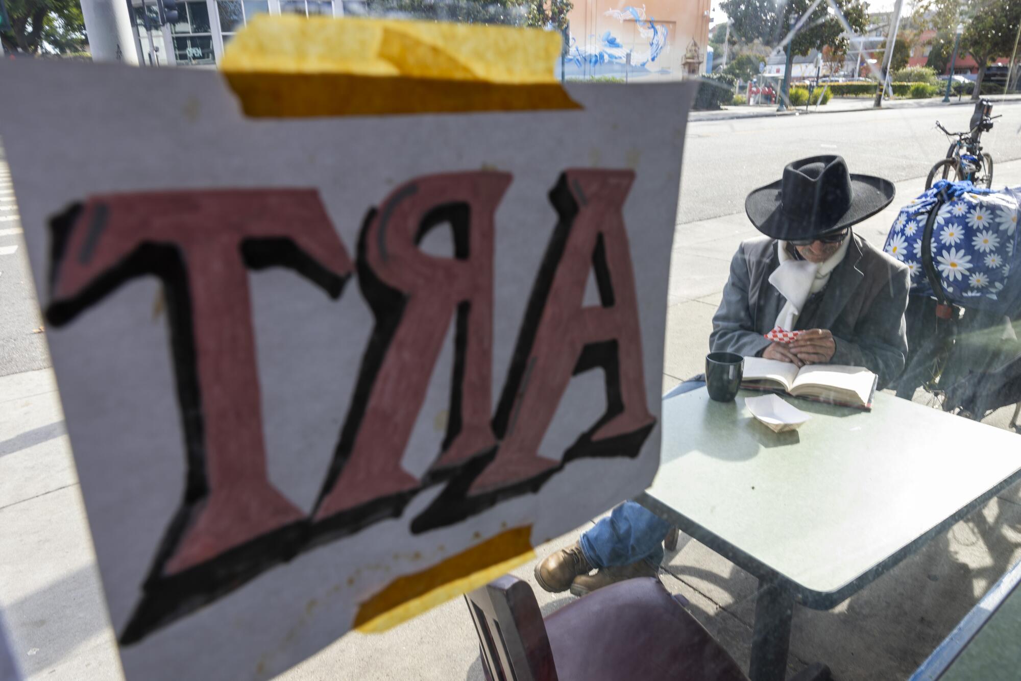 Một người đàn ông đọc sách tại quán cà phê vỉa hè ở Santa Cruz.
