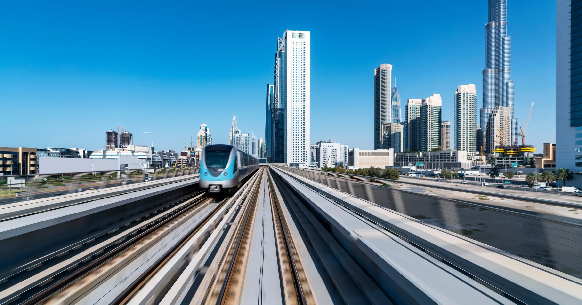 Birleşik Arap Emirlikleri, Dubai, Dubai Metrosu toplu taşıma sistemindeki raylarda ilerleyen trenin içinden şehir manzarasının uzaktan görünümü.