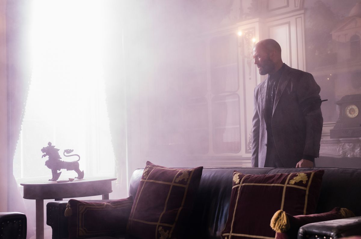 Jason Statham arde en una habitación brillantemente iluminada con muebles y decoraciones elegantes en The Beekeeper.