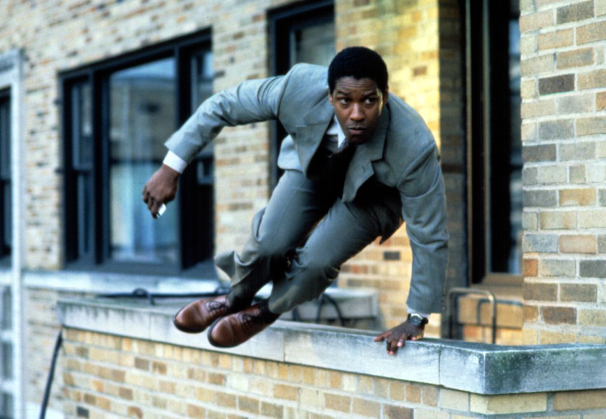 Denzel Washington, vestido con traje, salta una cornisa en The Pelican Brief.