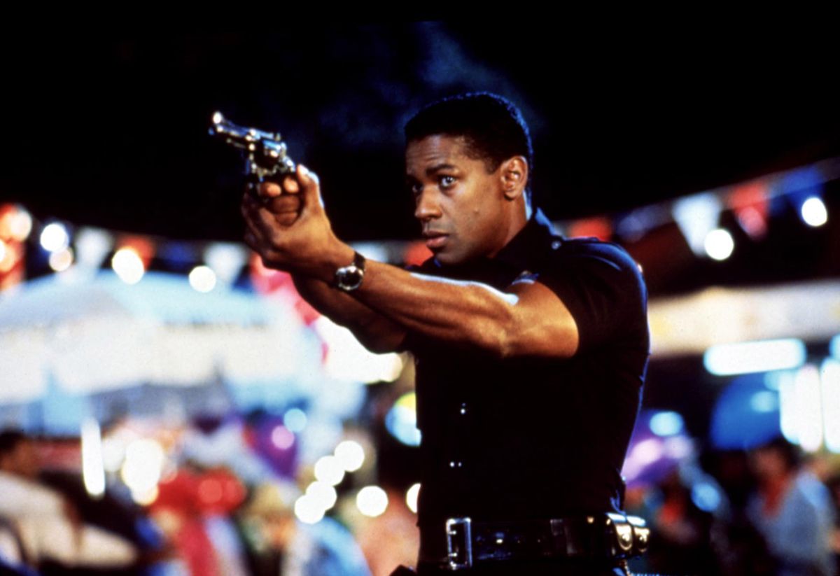 Genç Denzel Washington, Ricochet'te polis üniforması giyerken tabancasıyla nişan alıyor.