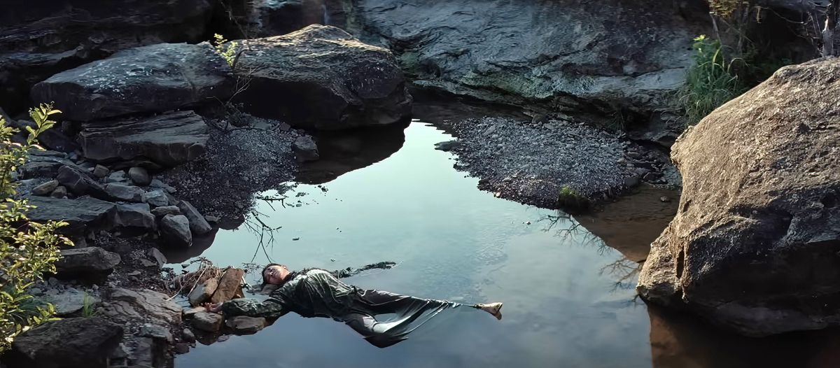 Il cadavere di una donna nativa giace in una piccola pozza tra rocce e ghiaia in una scena di Killers of the Flower Moon di Martin Scorsese