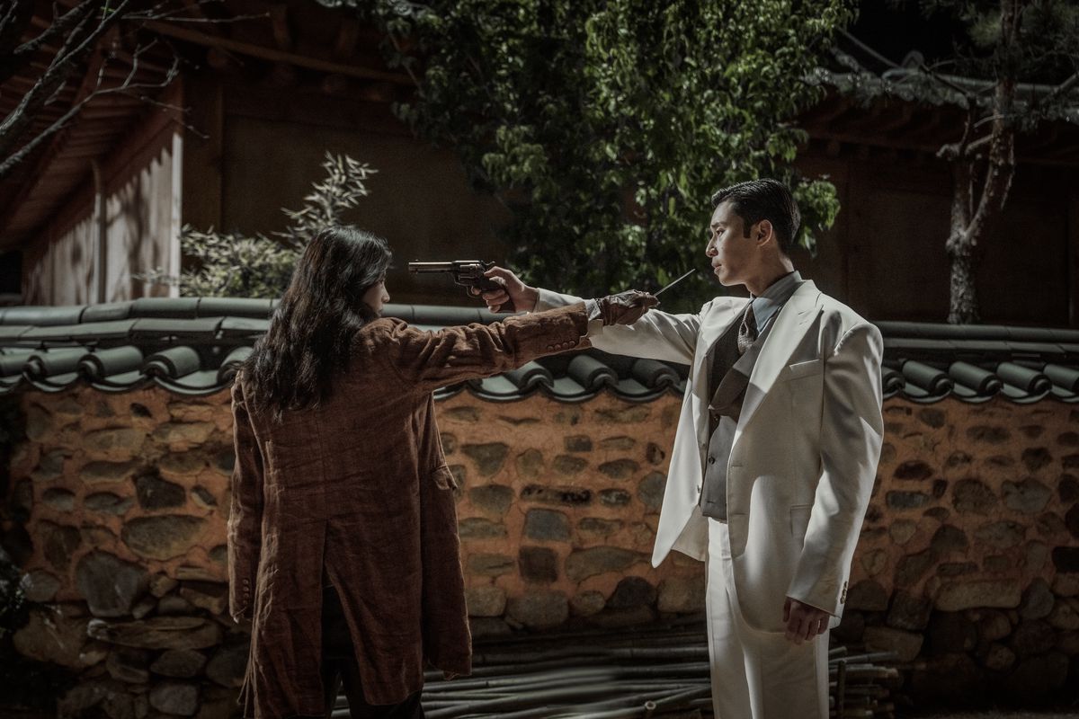 Les deux protagonistes de Gyeongseong Creature se tiennent debout, l'un pointant une arme sur l'autre et l'autre tenant un couteau en réponse.