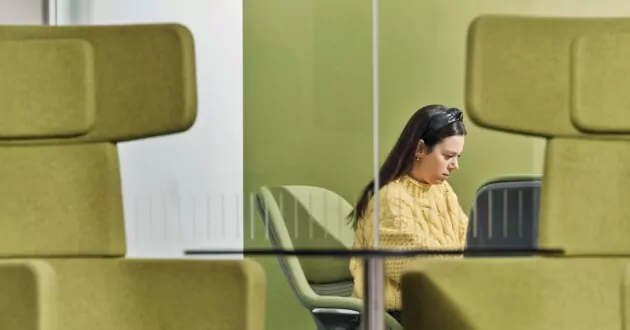 Person auf Laptop zwischen grünen Stühlen bei IBM