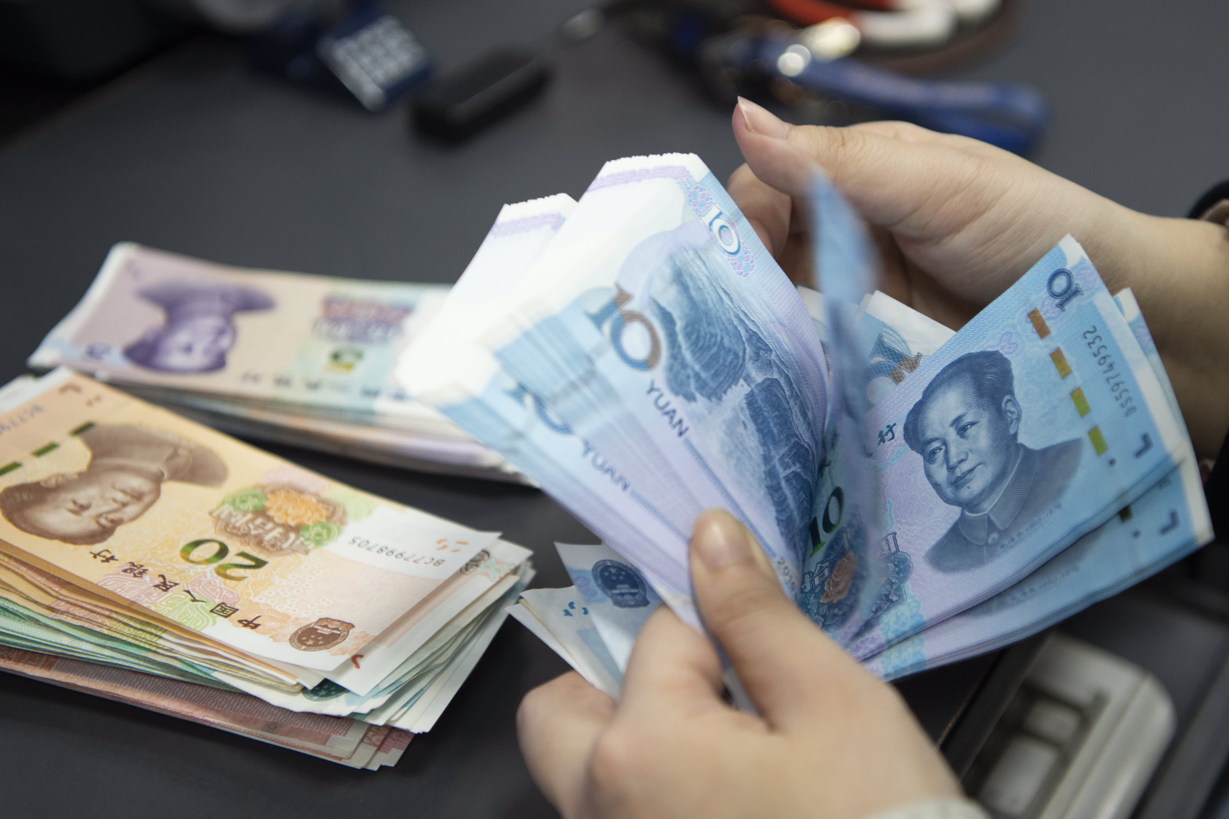 HAIAN, CHINA - JANUARY 24, 2024 - A staff member of the personal finance business area of a bank counts and arranges the RMB deposited by customers in the daily account in Haian city, Jiangsu province, China, Jan 24, 2024. (Photo credit should read CFOTO/Future Publishing via Getty Images)