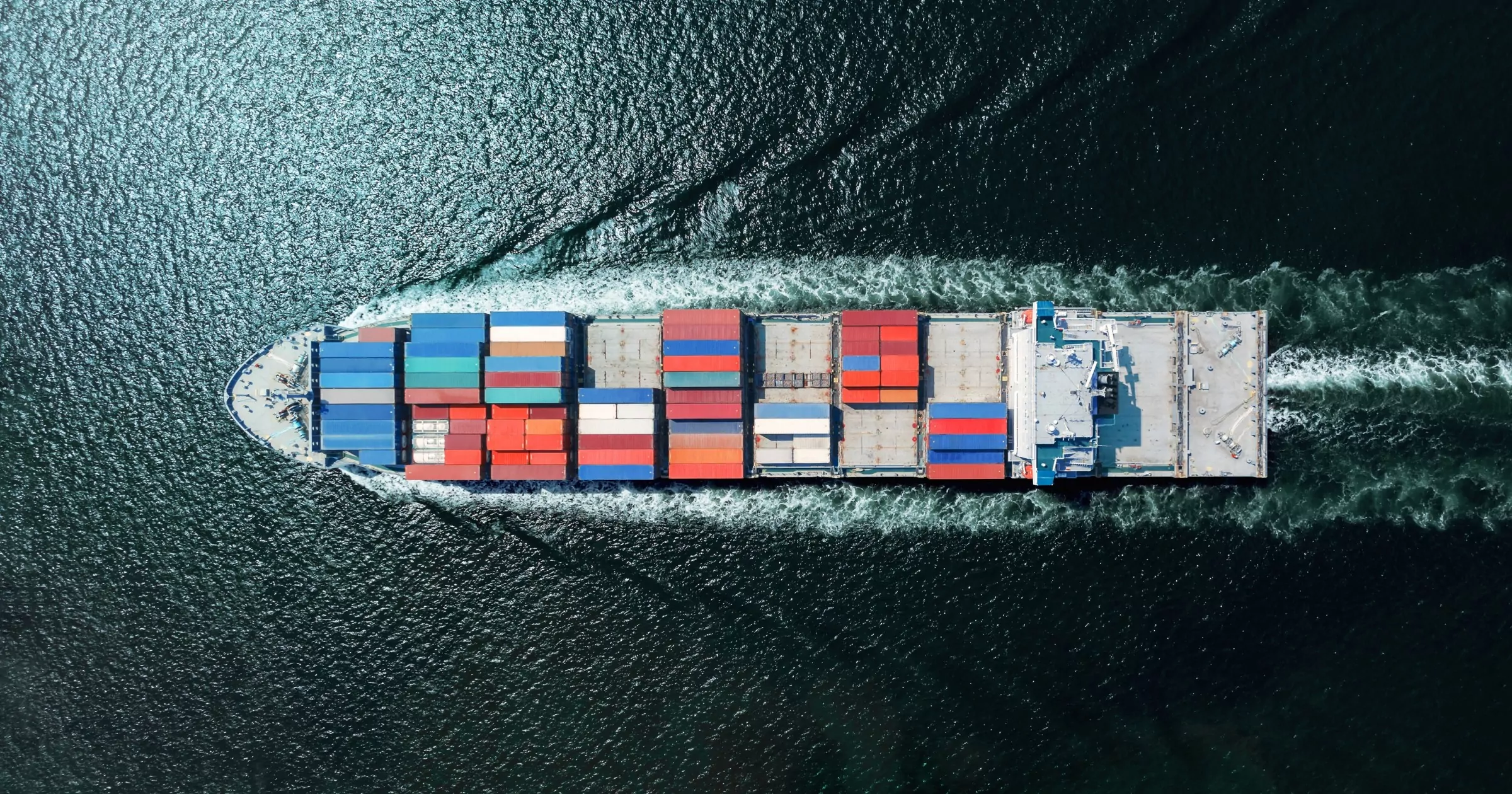 Luftfoto av skip med fraktcontainere som beveger seg gjennom vann